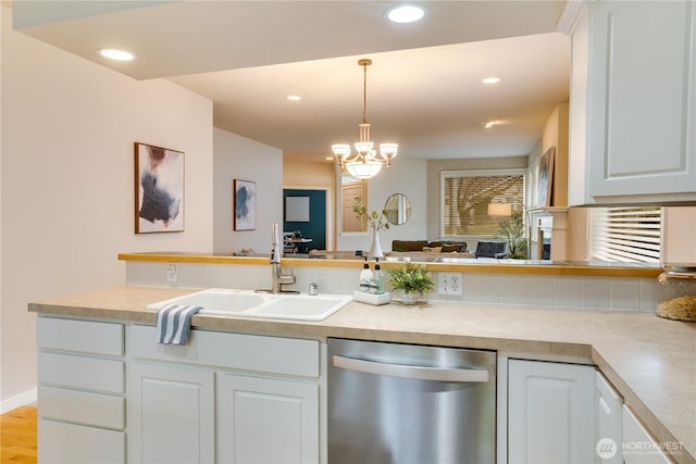 kitchen with pendant lighting, light countertops, stainless steel dishwasher, white cabinets, and a sink