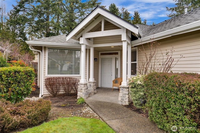 entrance to property featuring roof with shingles