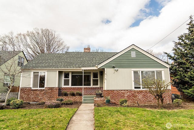 view of front facade featuring a front yard, a chimney, and brick siding