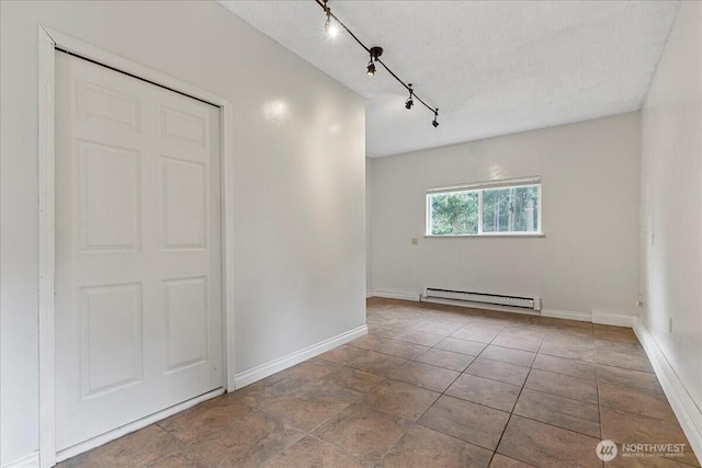 unfurnished room featuring rail lighting, baseboards, a textured ceiling, and baseboard heating