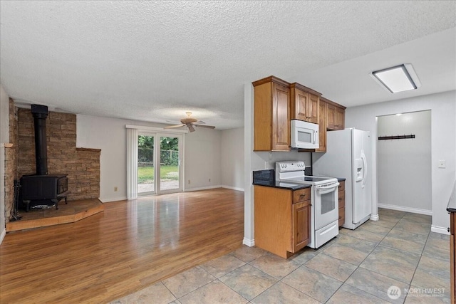 kitchen featuring white appliances, a ceiling fan, open floor plan, light wood-type flooring, and a wood stove