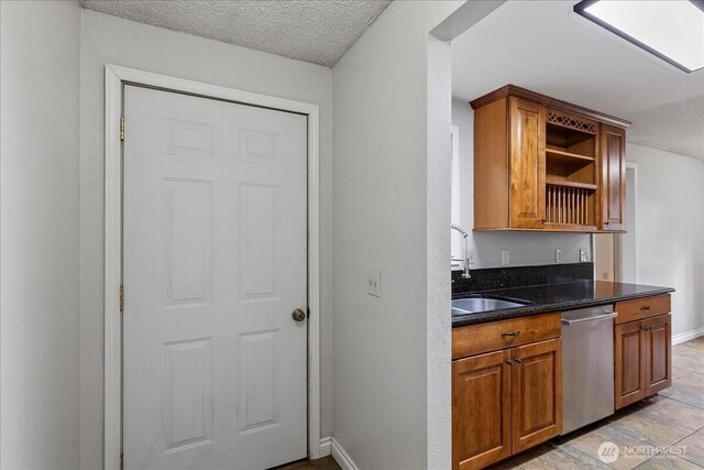 kitchen featuring a textured ceiling, a sink, brown cabinets, dishwasher, and open shelves