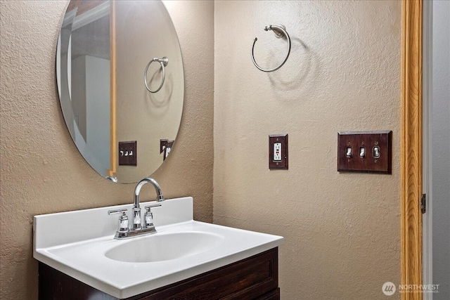 bathroom with a textured wall and vanity