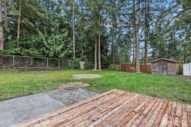 view of yard with a fenced backyard, an outdoor structure, a wooden deck, and a storage unit