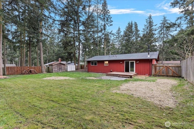 back of property featuring a yard, a shed, a fenced backyard, an outdoor structure, and a wooden deck