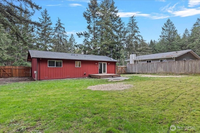 rear view of house featuring board and batten siding, a fenced backyard, a deck, and a lawn