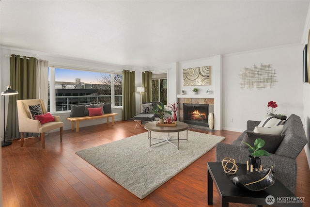 living area with a tiled fireplace, wood finished floors, and ornamental molding