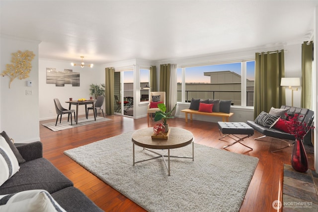 living room with hardwood / wood-style flooring, a notable chandelier, and baseboards