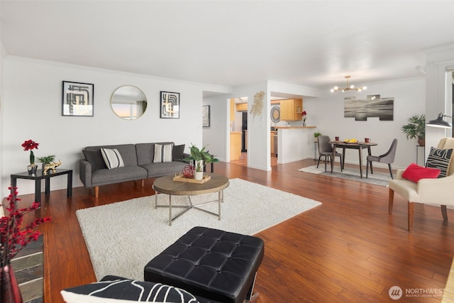 living room featuring an inviting chandelier, wood finished floors, and crown molding