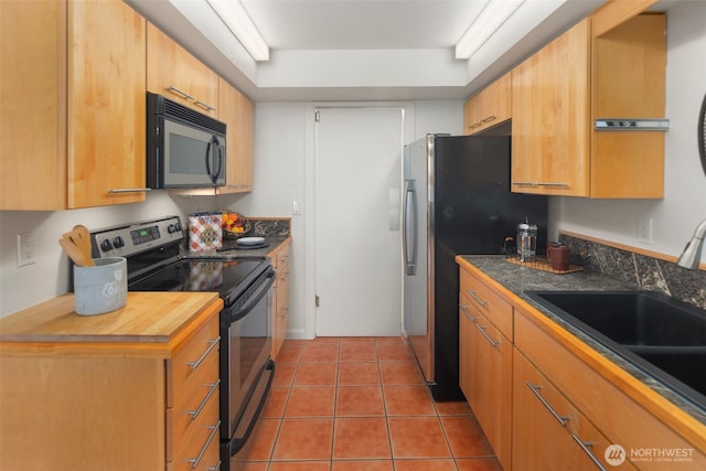 kitchen featuring light tile patterned floors, appliances with stainless steel finishes, a tray ceiling, and a sink