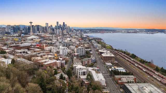 aerial view at dusk featuring a view of city and a water view