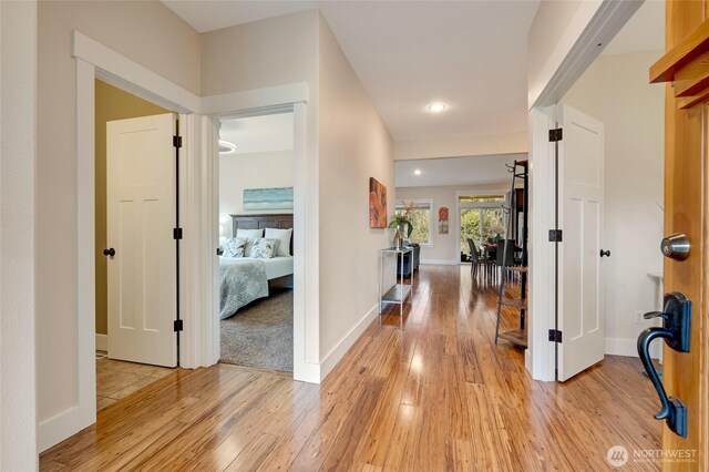 hallway featuring light wood-type flooring, baseboards, and recessed lighting