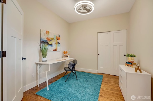 office area with light wood finished floors, built in study area, and baseboards