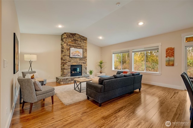 living room featuring vaulted ceiling, light wood-type flooring, a fireplace, and baseboards