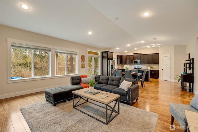 living area featuring lofted ceiling, baseboards, light wood finished floors, and recessed lighting