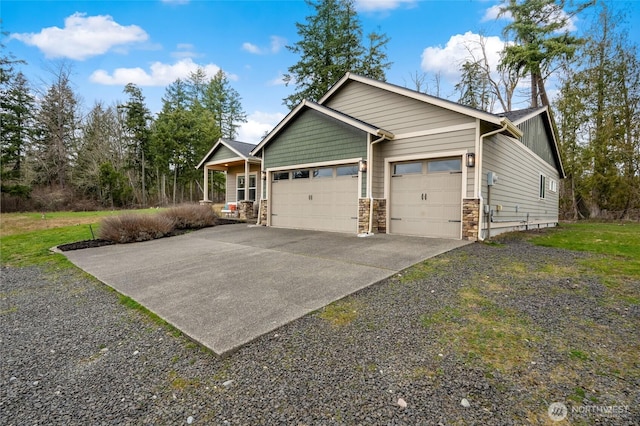 view of side of property featuring driveway, stone siding, and an attached garage