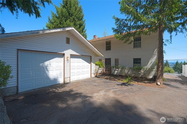 view of front facade with a garage, an outdoor structure, and driveway