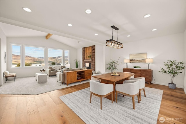 dining space featuring vaulted ceiling with beams, light wood finished floors, a fireplace, and recessed lighting