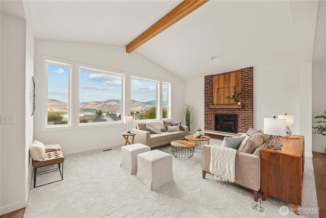 living area featuring vaulted ceiling with beams, a fireplace, carpet flooring, a mountain view, and baseboards