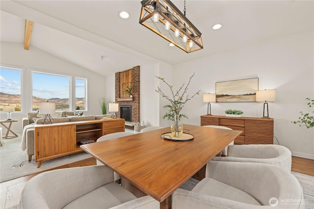 dining room with baseboards, light wood-style flooring, vaulted ceiling with beams, a fireplace, and recessed lighting