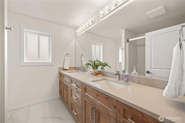 bathroom with double vanity, marble finish floor, baseboards, and a sink