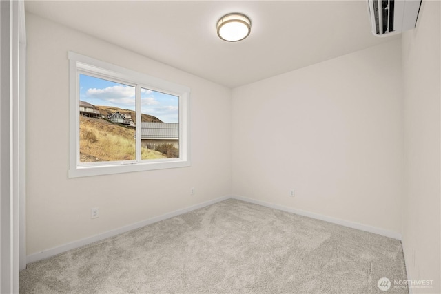 carpeted spare room featuring baseboards