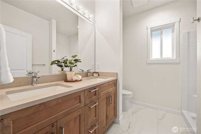 bathroom featuring toilet, marble finish floor, baseboards, and a sink