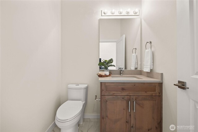 bathroom with toilet, marble finish floor, baseboards, and vanity