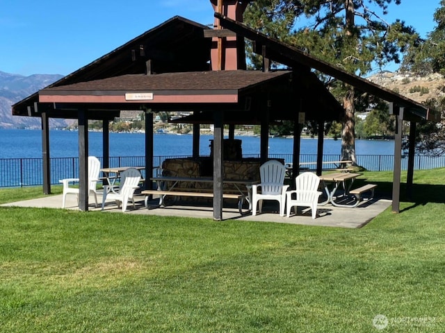 view of dock featuring a yard, a water view, and fence