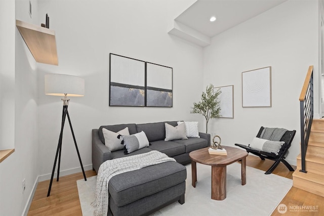 living room featuring light wood-type flooring, recessed lighting, baseboards, and stairs