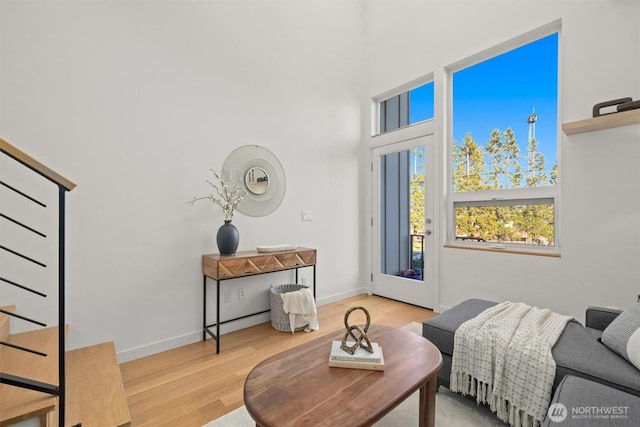 interior space featuring a towering ceiling, stairway, baseboards, and wood finished floors