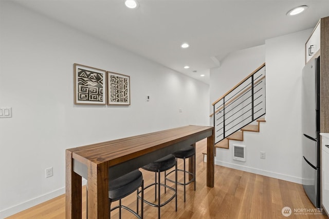 dining area featuring recessed lighting, visible vents, baseboards, light wood-style floors, and stairway