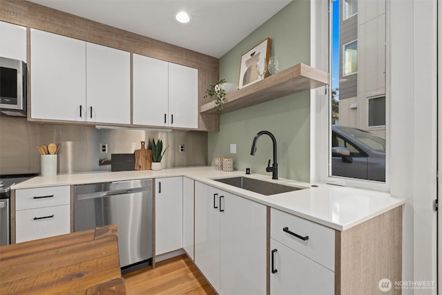 kitchen with open shelves, stainless steel appliances, light countertops, white cabinets, and a sink