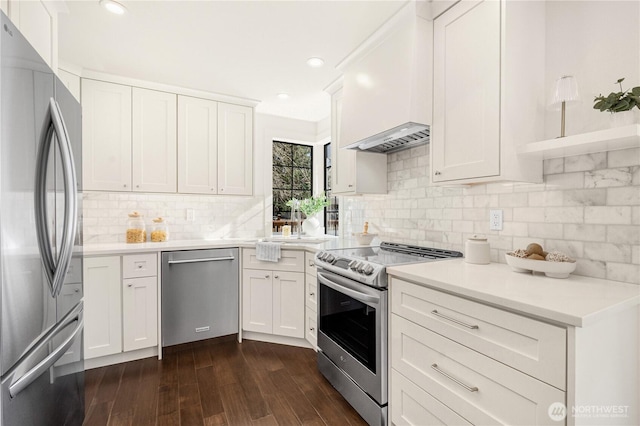 kitchen featuring custom range hood, dark wood-type flooring, stainless steel appliances, light countertops, and white cabinetry