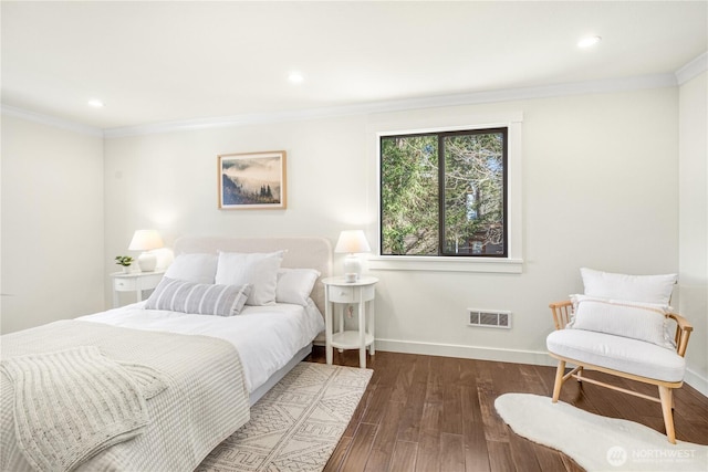 bedroom with baseboards, visible vents, crown molding, and wood finished floors