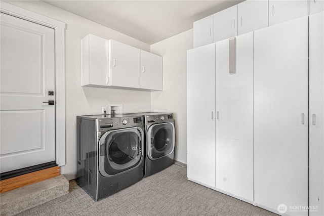 clothes washing area featuring washing machine and dryer and cabinet space