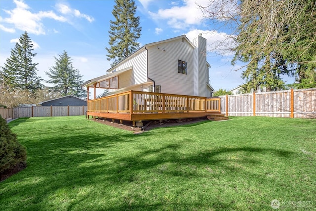 rear view of house featuring a deck, a lawn, a chimney, and a fenced backyard