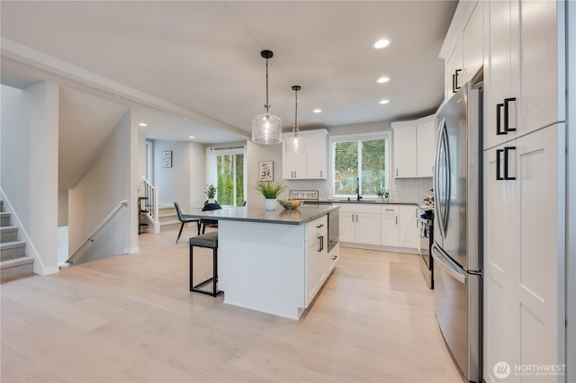 kitchen featuring dark countertops, white cabinetry, a breakfast bar, and freestanding refrigerator