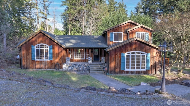 view of front of home with roof with shingles and fence