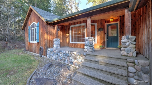 property entrance with a porch and roof with shingles