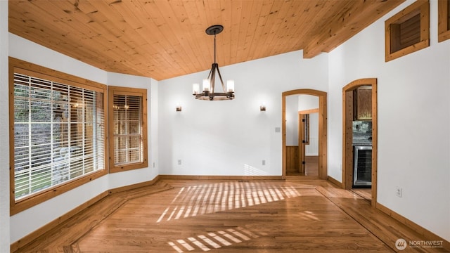 unfurnished dining area with wood ceiling, wine cooler, arched walkways, and wood finished floors