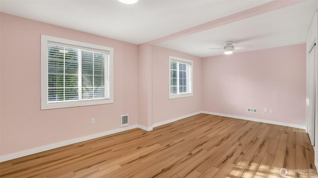 spare room featuring baseboards, visible vents, ceiling fan, and wood finished floors