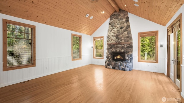 unfurnished living room with a stone fireplace, beamed ceiling, wood finished floors, and wood ceiling