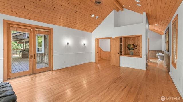 unfurnished living room featuring light wood-style floors, wood ceiling, wainscoting, and beamed ceiling