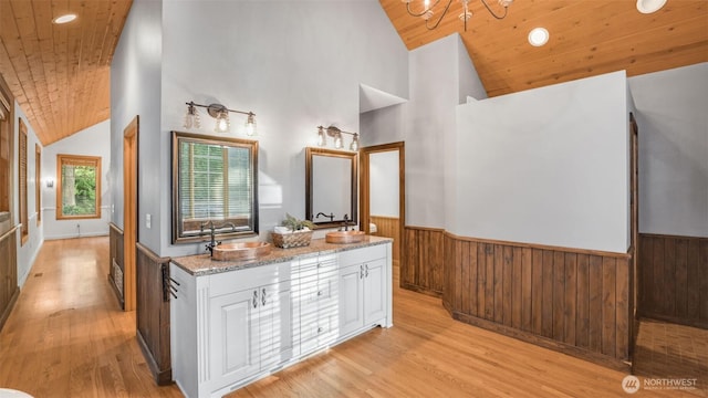 bathroom with wainscoting, wooden ceiling, wood finished floors, wood walls, and a sink