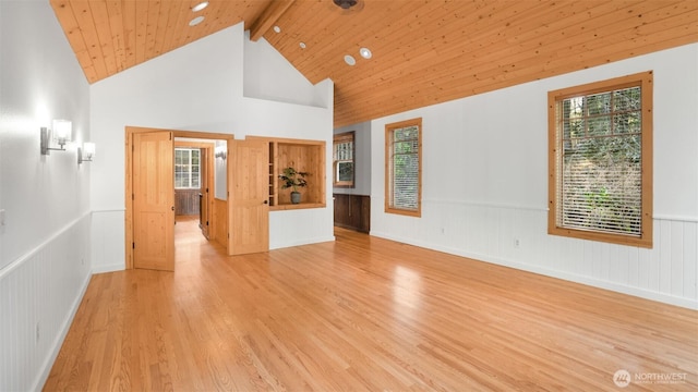 unfurnished room featuring wainscoting, wooden ceiling, light wood-type flooring, high vaulted ceiling, and beam ceiling