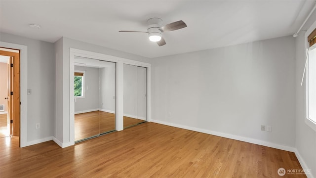 unfurnished bedroom with light wood-type flooring, baseboards, and two closets