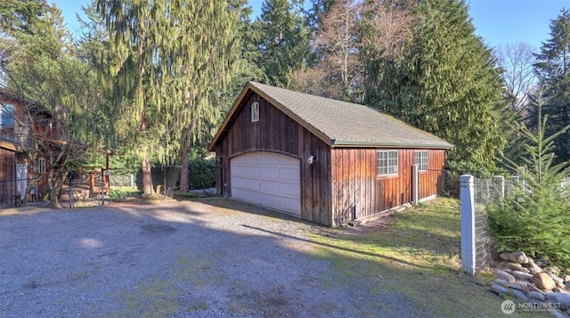 detached garage featuring driveway and fence