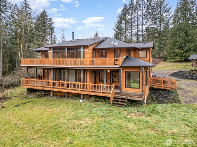 rear view of house featuring a shingled roof, a deck, and a yard