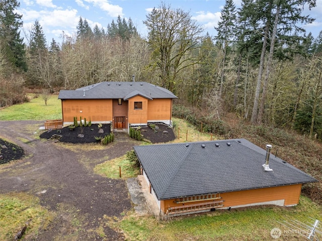 rear view of house with driveway and a wooded view